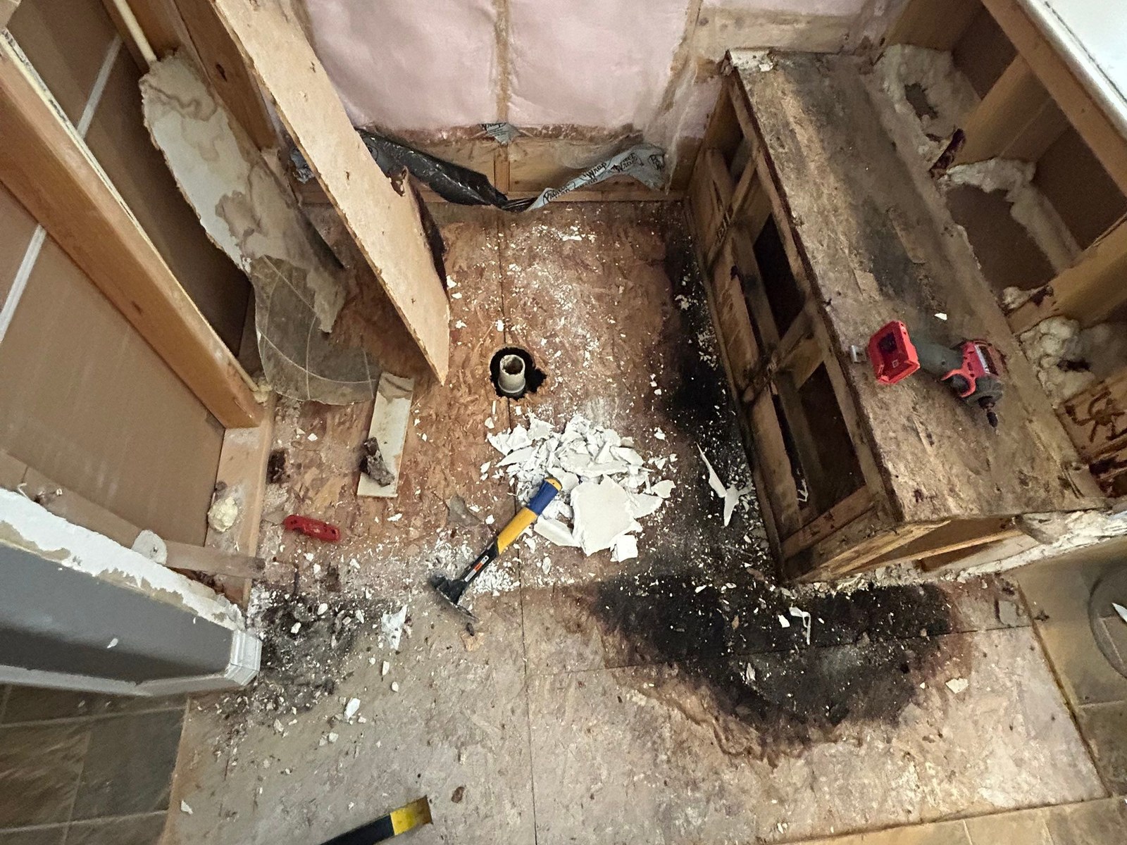 Opened shower enclosure exposing moisture-damaged materials and subfloor.
